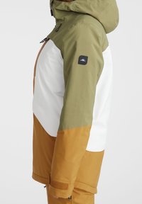 Kurtka z oliwkowo-zielonym kapturem i rękawami, białym panelem na klatce piersiowej oraz musztardowo-żółtymi dolnymi rękawami i dołem, z czarną naszywką z logo na ramieniu.