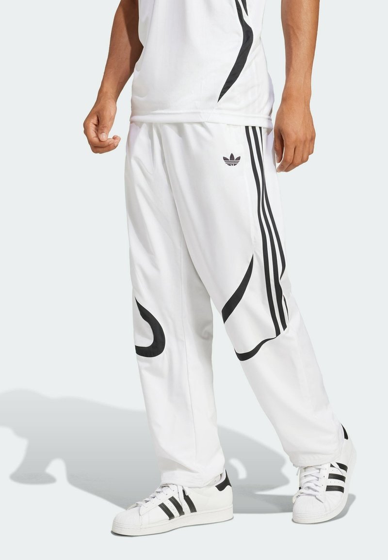 Vita träningsbyxor med svarta sidostreck och abstrakt design. Tillverkade av ett slätt tyg, med en broderad logotyp nära höften.