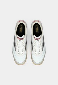 Witte leren sneakers met een gumrubberen zool, zwarte accenten en een rood logo. Heeft een vetersluiting en een gevoerde kraag voor comfort.