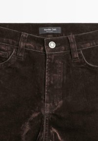 Pantaloni in velluto marrone scuro con bottone frontale, passanti per cintura, tasche e etichetta "Massimo Dutti Made in Turkey" all'interno del cinturino.