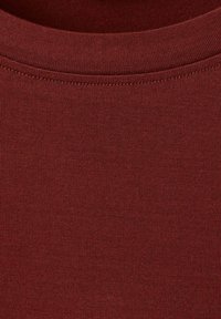 Bordowa koszulka z krótkim rękawem wykonana z miękkiej bawełny, z okrągłym dekoltem, prążkowaną fakturą i bezszwową konstrukcją ramion. Bez widocznych wzorów.