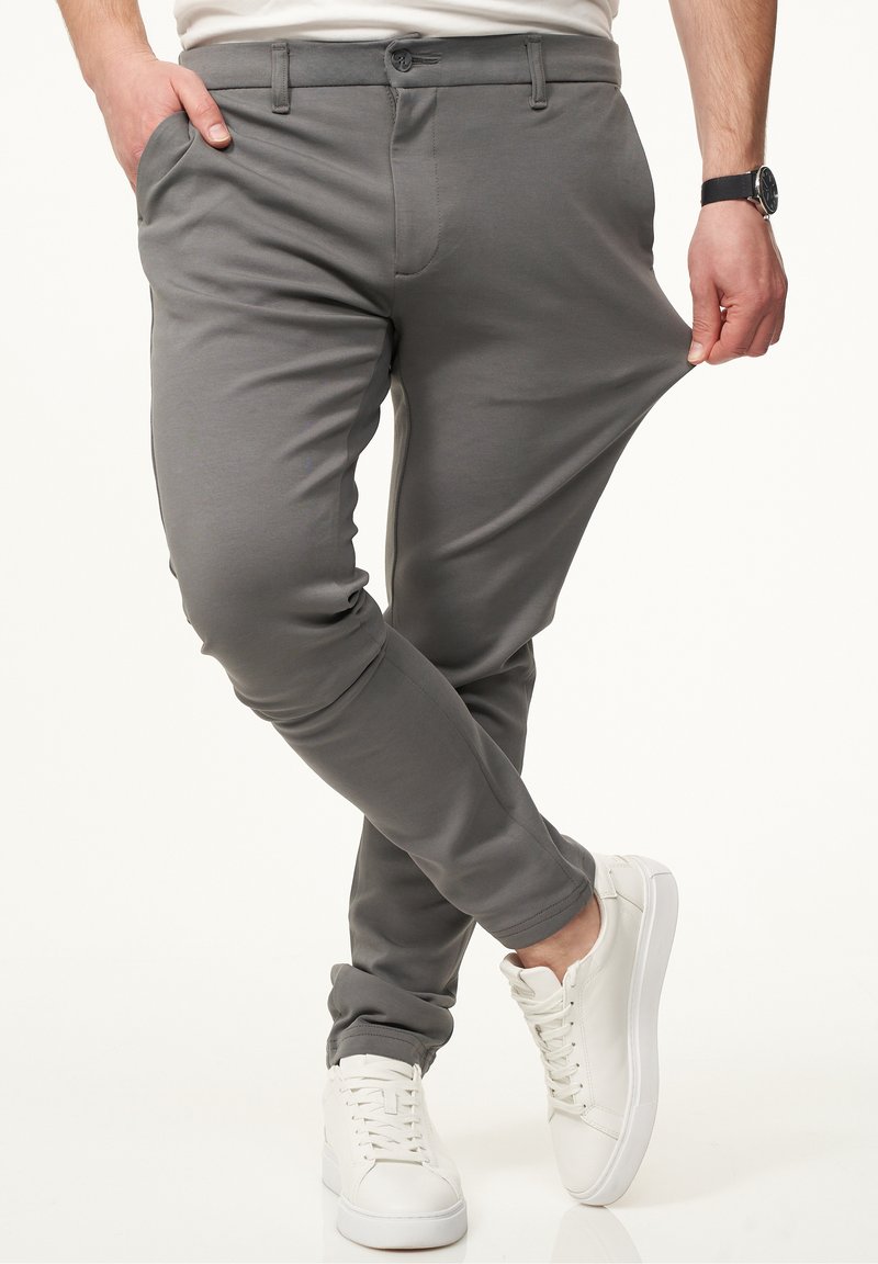 Gray pants with a slim fit, made from lightweight fabric, featuring side pockets and a button closure, paired with white sneakers.