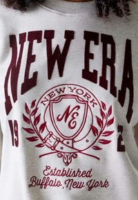 Felpa grigia con testo color bordeaux: "NEW ERA" accompagnato da un logo con uno scudo, rami di alloro decorativi e la dicitura "Established Buffalo, New York."