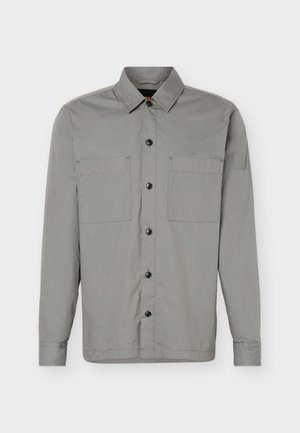 Hall hall varrukatega särgi, millel on kaks rinnataskut, terav krae ja vasaku üla-varruka peal logomärk.