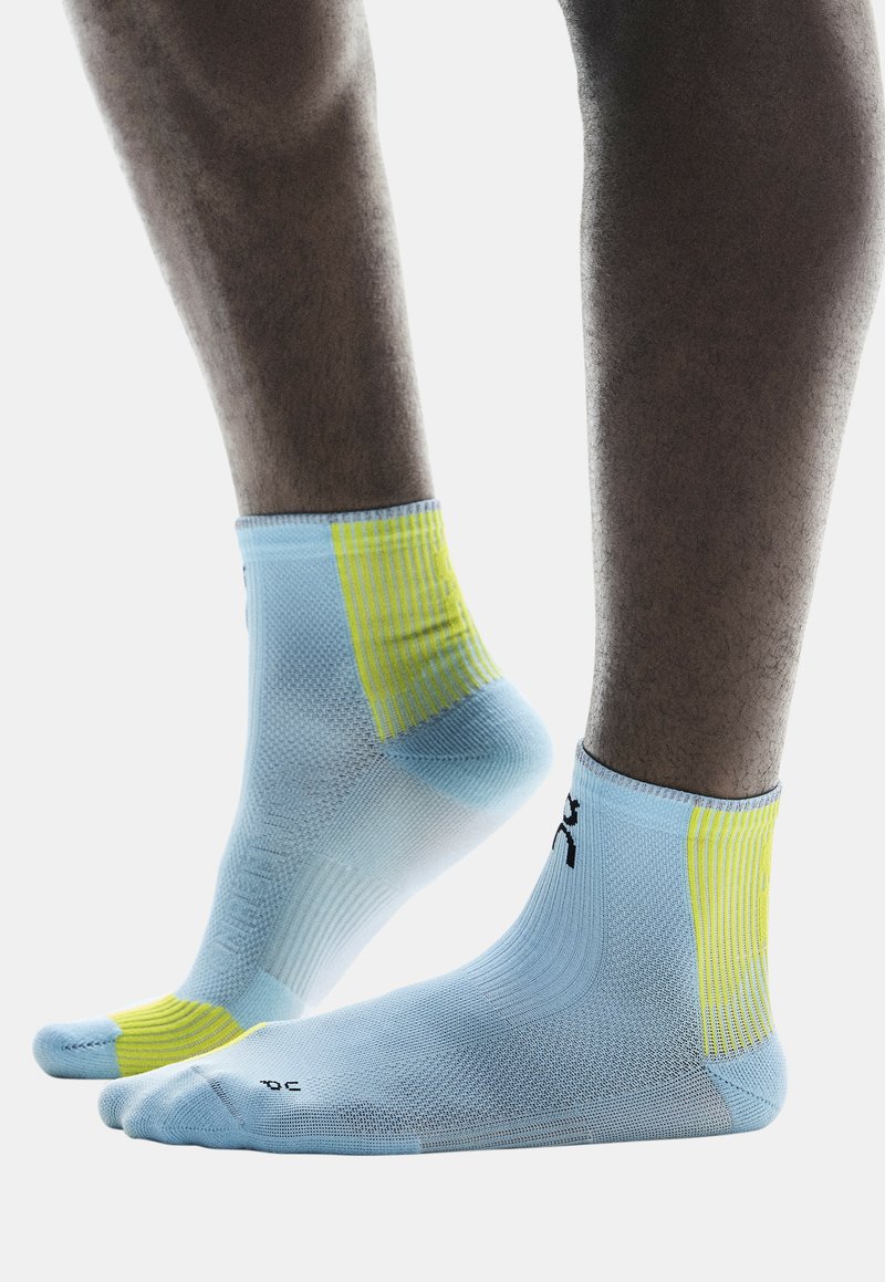 Blaue Sportsocken mit gelben Akzenten, aus strukturiertem Stoff, knöchelhoch, mit engem Sitz und einem Logo, das in der Nähe des Bündchens aufgedruckt ist.