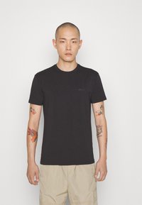 T-shirt nera a collo rotondo realizzata in cotone con una leggera elasticità; presenta un branding minimale sul petto e maniche corte.