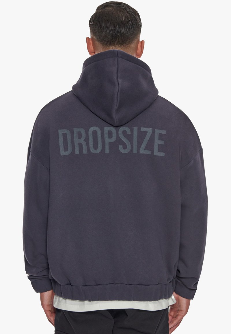 Mørkegrå oversized hoodie med snoretræk i hætten og ordet "DROPSIZE" trykt med store bogstaver på ryggen. Blødt stof.