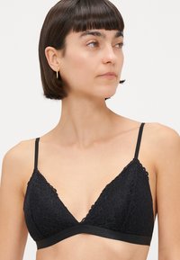 Black lace triangle bra with adjustable straps and a smooth fabric band. Features floral patterns along the lace edges.