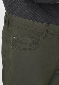 Green cotton blend pants with a classic five-pocket design, featuring subtle stitching details and a button closure.