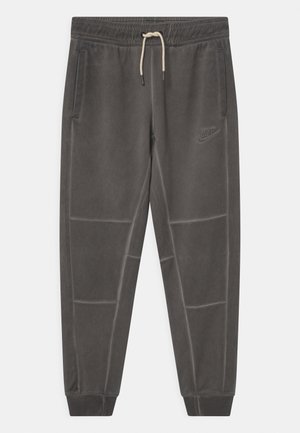 Szare spodnie dresowe Nike z elastycznym pasem, sznurkiem do regulacji, bocznymi kieszeniami i ściągaczami na nogawkach. Dyskretne logo na udzie. Miękka tekstura.