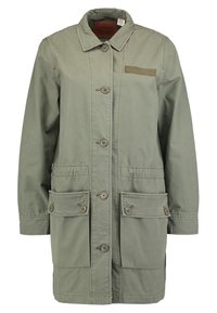 Giacca verde oliva di lunghezza media con chiusura a bottoni, due grandi tasche frontali e una piccola tasca sul petto. Realizzata in tessuto resistente.