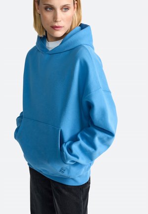 Sky blue hooded sweatshirt with a front pocket, loose fit, and ribbed cuffs and hem. Soft fabric with a subtle logo accent near the hem.