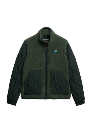 Veste en polaire verte duveteuse avec une section inférieure matelassée et deux poches avant. Comprend un col montant et une fermeture éclair. Patch logo sur la poitrine.