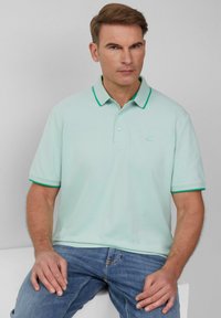 Licht mintgroen poloshirt met een effen ontwerp, contrasterende donkergroene kraag en mouwaccenten, gemaakt van een zachte, gestructureerde stof.