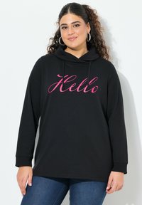 Sudadera con capucha negra que presenta un gráfico en cursiva rosa que dice "Hola", con mangas largas, un corte relajado y un material de algodón suave.