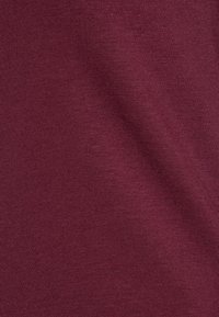 Burgundystoff med en glatt tekstur, fint ribbemønster og jevn farge. Ingen tilleggsmønstre eller aksenter er til stede.