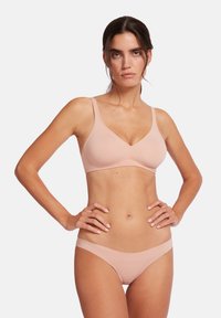 Persikofärgad trådlös bh med en mjuk textur, v-formad halsringning och breda axelband, i kombination med matchande låga bikiniunderbyxor.