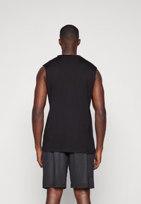 Black sleeveless shirt made of cotton, featuring a round neck and a relaxed fit, paired with black mesh shorts. Textured fabric details visible.
