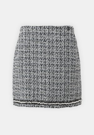Gonna mini in tweed bianco e nero con un motivo testurizzato, caratterizzata da un orlo con perle e un design aderente.
