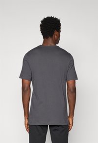 T-shirt gris foncé à manches courtes avec un col rond et une coupe standard. Fabriqué en coton, texture lisse, design uni sans motifs.