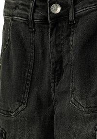 Schwarze Denim-Jeans mit Knopfverschluss, ausgestattet mit frontalen Taschen und strukturiertem Stoff. Das Design der hinteren Tasche ist sichtbar und zeigt Nähdetails.