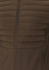Brown insulated jacket featuring a quilted design with horizontal seams, full zipper closure, and side pocket with zip. Soft, smooth texture.