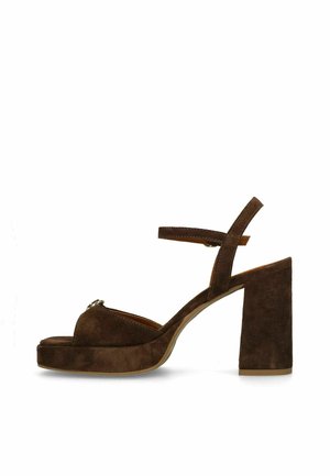 Bruine suède slippers met plateauzool, enkelbandje en stevige hoge hak, zijaanzicht op witte achtergrond.