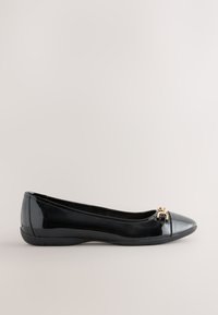 Black patent leather flat shoe with rounded toe and small gold decorative buckle on front, plain light background.