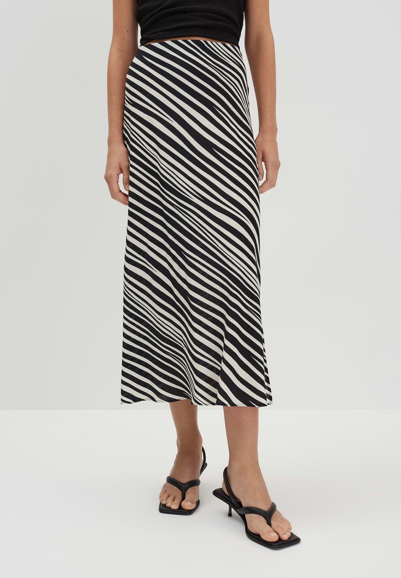 Gonna a righe bianche e nere con un design fluido, di lunghezza media, realizzata in tessuto leggero, con una vita comoda e una silhouette snella.