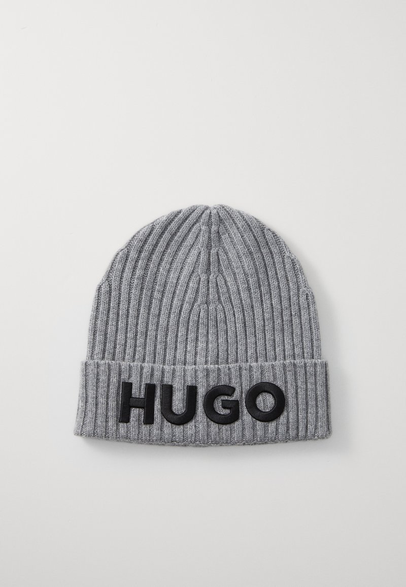 Beanie grigio lavorato a maglia con texture a coste e risvolto. Presenta una grande scritta nera "HUGO" sul davanti. Design classico e colore semplice.