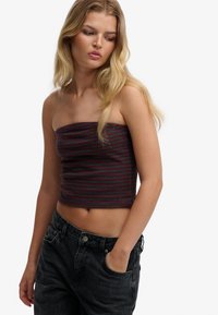 Strapless, cropped top in dark gray with burgundy horizontal stripes, made from soft fabric. Paired with high-waisted black jeans.