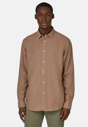 Camisa marrón de manga larga con botones, cuello puntiagudo, tela texturizada y botones blancos, combinada con pantalones verde claro.