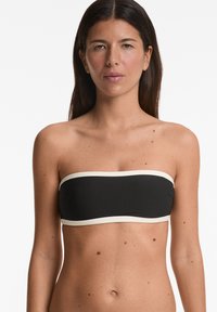 Črn bandeau top z kremastim obrobom, gladka tekstura in minimalističen dizajn. Brez naramnic, z enostavno in čisto obliko.