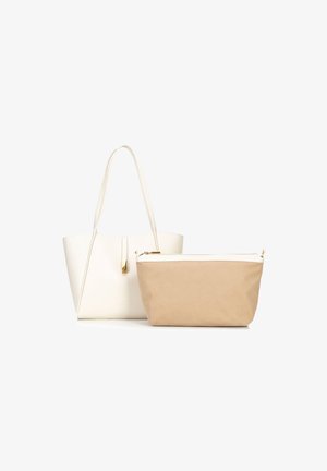 Bolso tote estructurado blanco con asas largas y herrajes dorados al lado de un estuche con cremallera color marrón y borde superior blanco.
