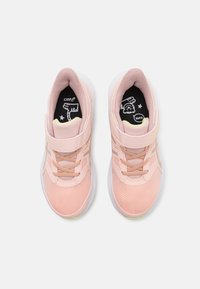 Baskets de sport rose clair avec empeigne en maille, accents synthétiques, sangle ajustable et semelle en caoutchouc blanche. Semelle intérieure noire avec design graphique.