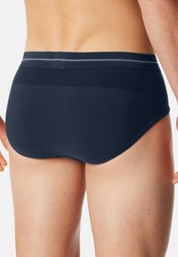 Dunkelblaue Low-Rise-Slips aus glattem Stoff, mit elastischem Bund und einem hellgrauen Streifen sowie einer enganliegenden Passform.