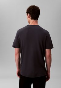 Dunkelgraues Baumwoll-T-Shirt mit kurzen Ärmeln, leichtem Stoff, Rundhalsausschnitt und glatter Textur, Rückansicht.