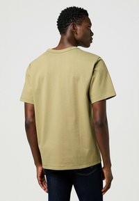 T-shirt verde oliva a maniche corte con scollatura rotonda, realizzato in morbido cotone, caratterizzato da una vestibilità comoda e dettagli di cucitura pulita.