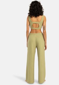 Ensemble vert olive en deux pièces avec un top court présentant un détail découpé et un pantalon à large jambe en tissu doux et texturé.