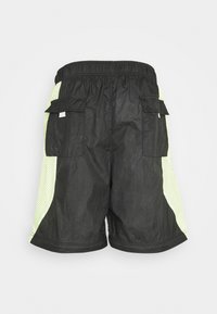 Svarta cargoshorts med en strukturerad yta, med neon-gula meshsidopaneler och flera sidofickor. Elastisk midja för bra passform.