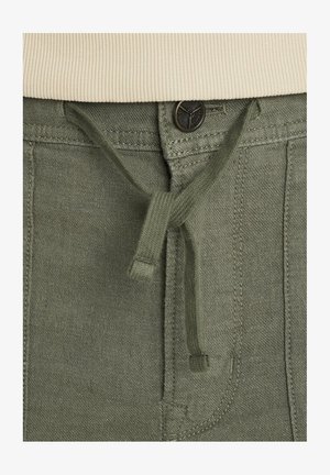 Zelené bavlnené nohavice s elastickým pásom a šnúrkou, vybavené kovovým gombíkom, bočnými vreckami a prešitím pre zvýraznenie textúry.