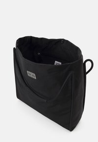 Svart tote-väska i strukturerad nylon, med en rymlig inredning, en zippered ficka och en märkesplatta på framsidan.