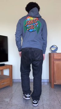 Hoodie cinza claro com gráfico multicolorido nas costas que apresenta um globo e texto, combinado com jeans pretos e ténis pretos.