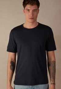 Námořnické modré tričko s kulatým výstřihem vyrobené z bavlny, s krátkými rukávy a hladkou texturou. Minimalistický design bez vzorů nebo log.