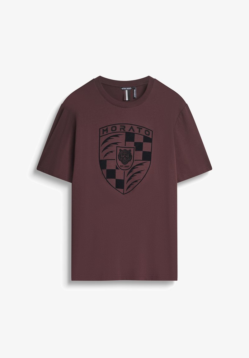 Camiseta marrón de algodón, con un logo de escudo negro que presenta un tigre y un patrón de cuadros. Mangas cortas, diseño de cuello redondo.