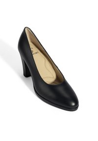 Chaussure à talon haut en cuir noir avec un bout pointu et un talon bloc modéré. L'intérieur est beige, montrant une texture lisse. Pas d'accents ou de motifs visibles.