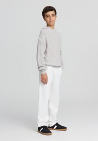 Jasnoszara, dziana bluza z kapturem, białe spodnie i czarne trampki z białymi paskami. Slim fit, długie rękawy i ściągacze. Prosty design.