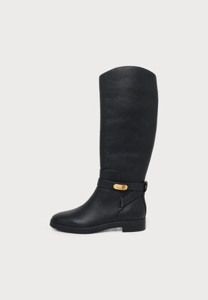 Botte en cuir noire montant jusqu’au genou, avec un talon bloc bas, une bride latérale et une boucle dorée.