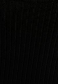 Svart ribbat tyg med en texturerad mönster, som har vertikala linjer. Materialet verkar mjukt och elastiskt.