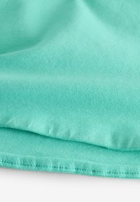 Een close-up van zacht, mintgroen katoenstof met een gladde textuur, die subtiele ribbels laat zien, gevouwen met schone randen.